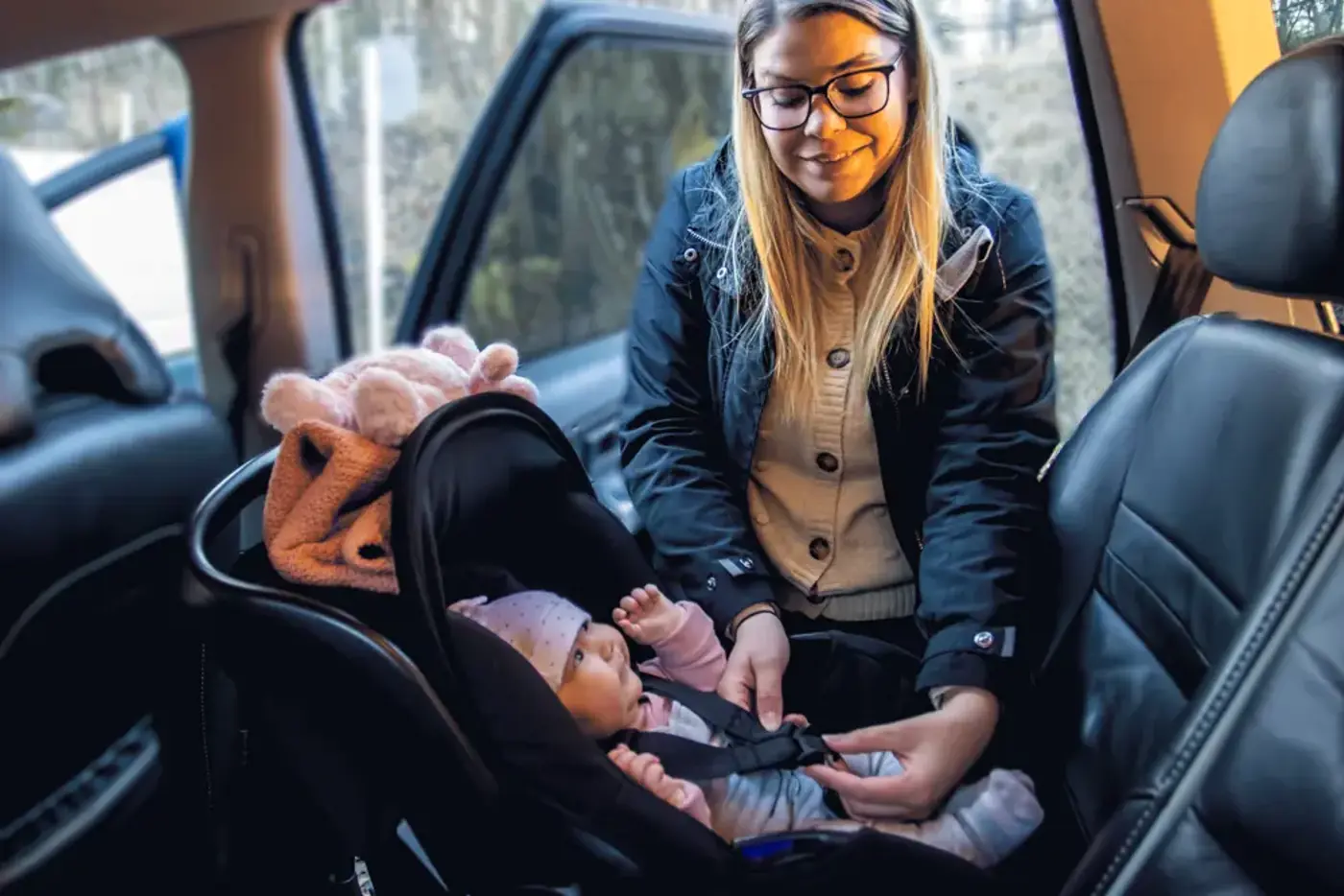 En mamma som spänner fast sin bebis i ett babyskydd i en bil.