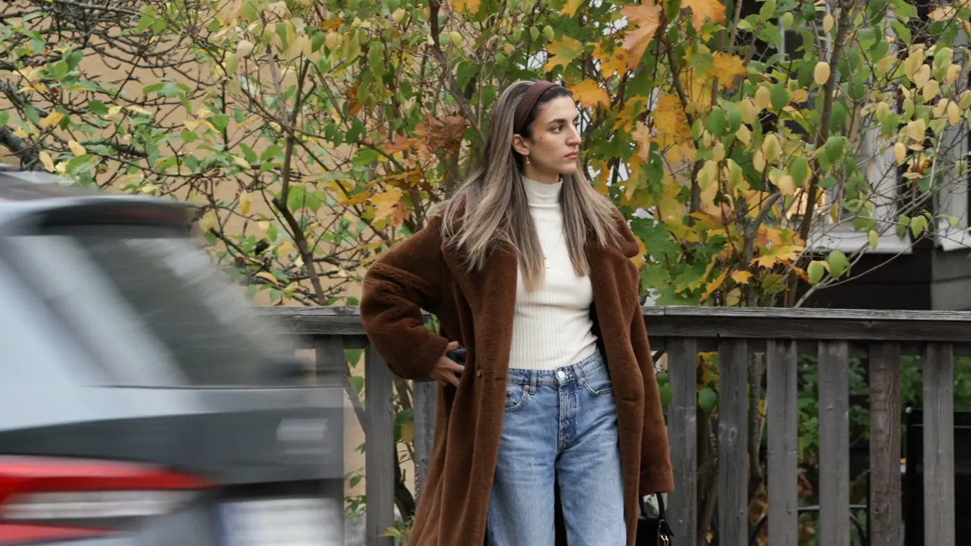 Kvinna vid ett staket och en bil som kör förbi