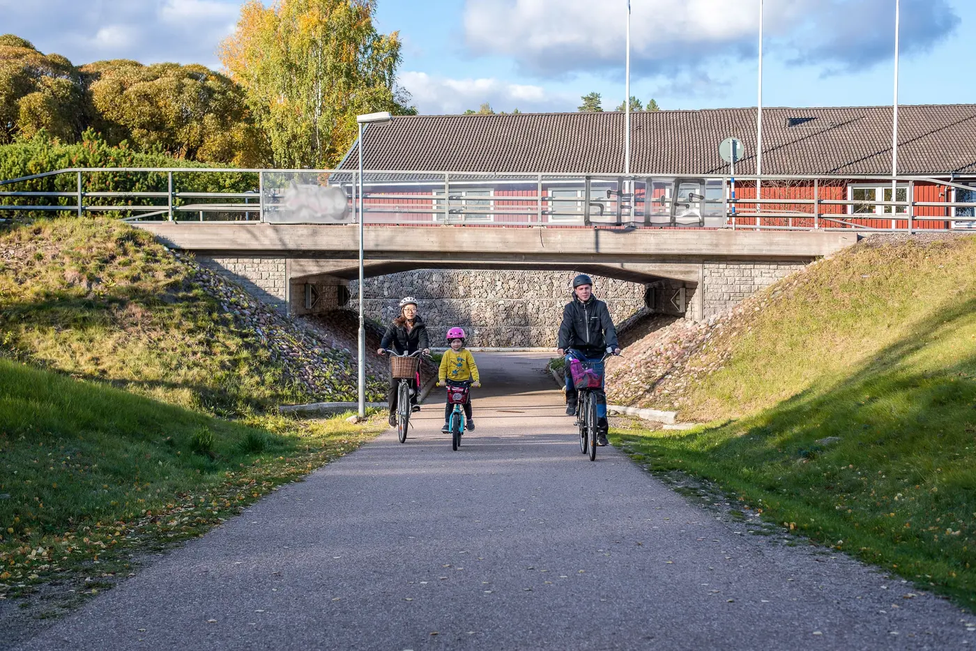 Två vuxna och ett barn cyklar ut genom en gångtunnel