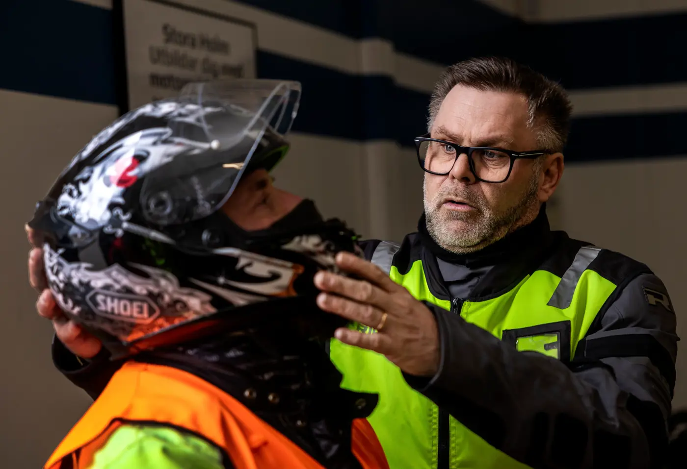 En person inspekterar MC-hjälmen på en annan person