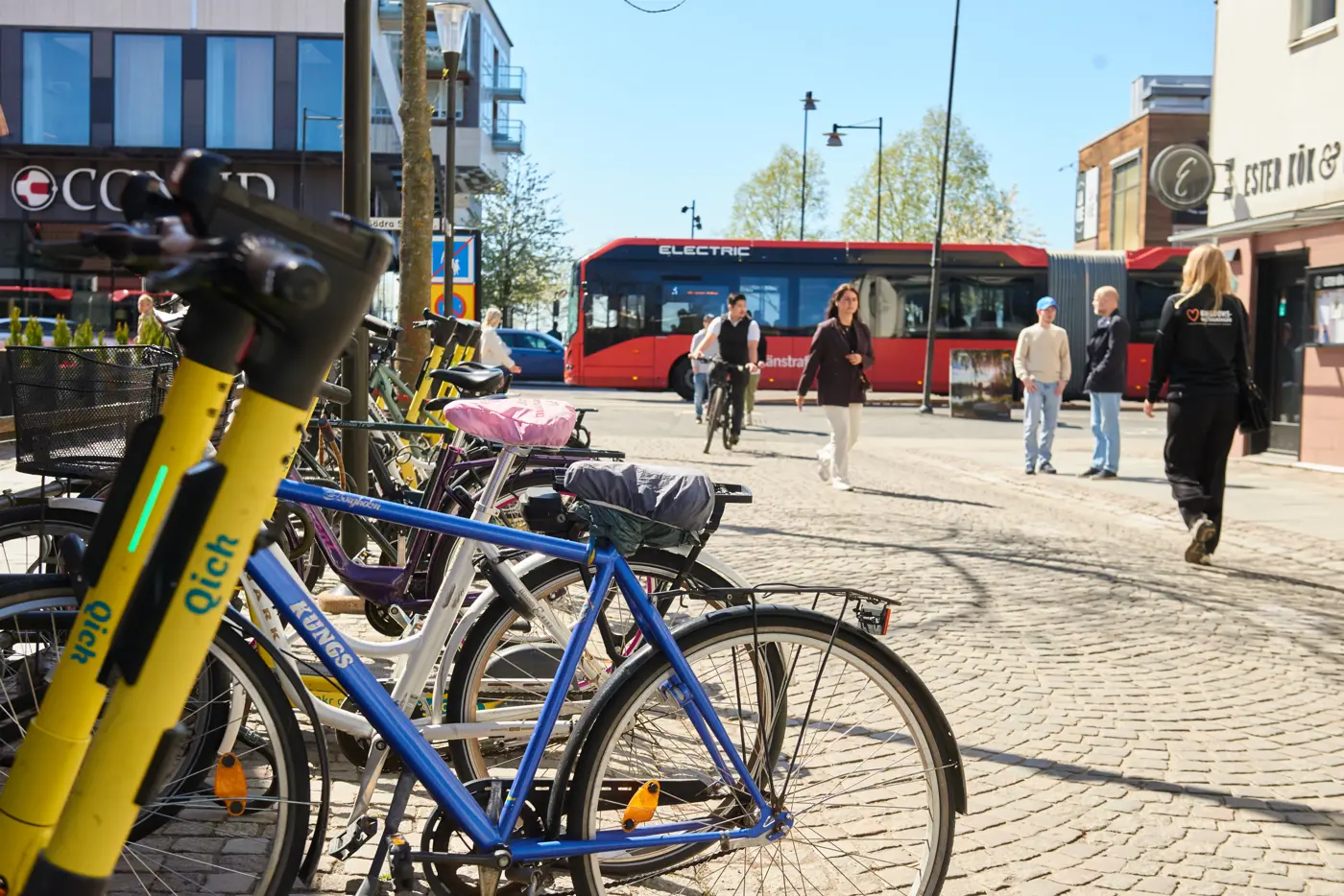 Elsparkcyklar och cyklar står parkerade i ett cykelställ.