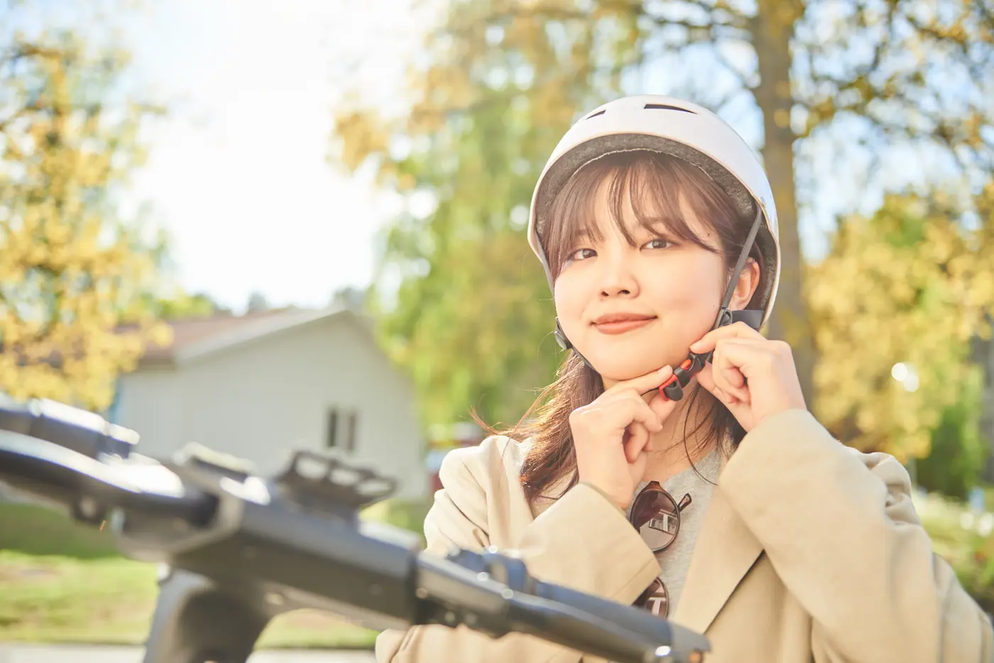 En ungdom står vid en elsparkcykel och knäpper på sig en hjälm.