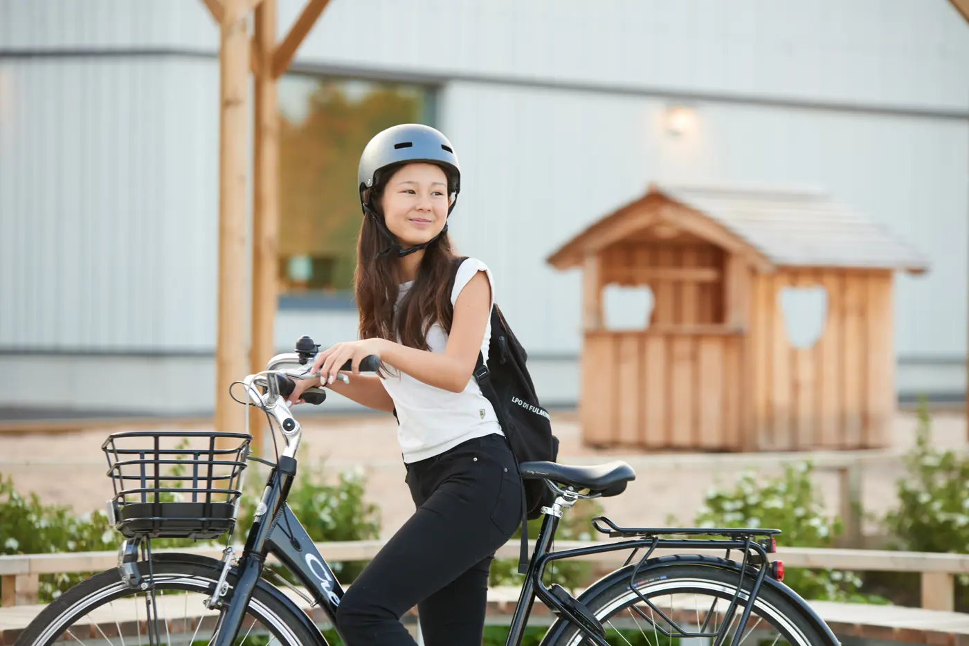 Ett skolbarn står med en cykel utanför en skola